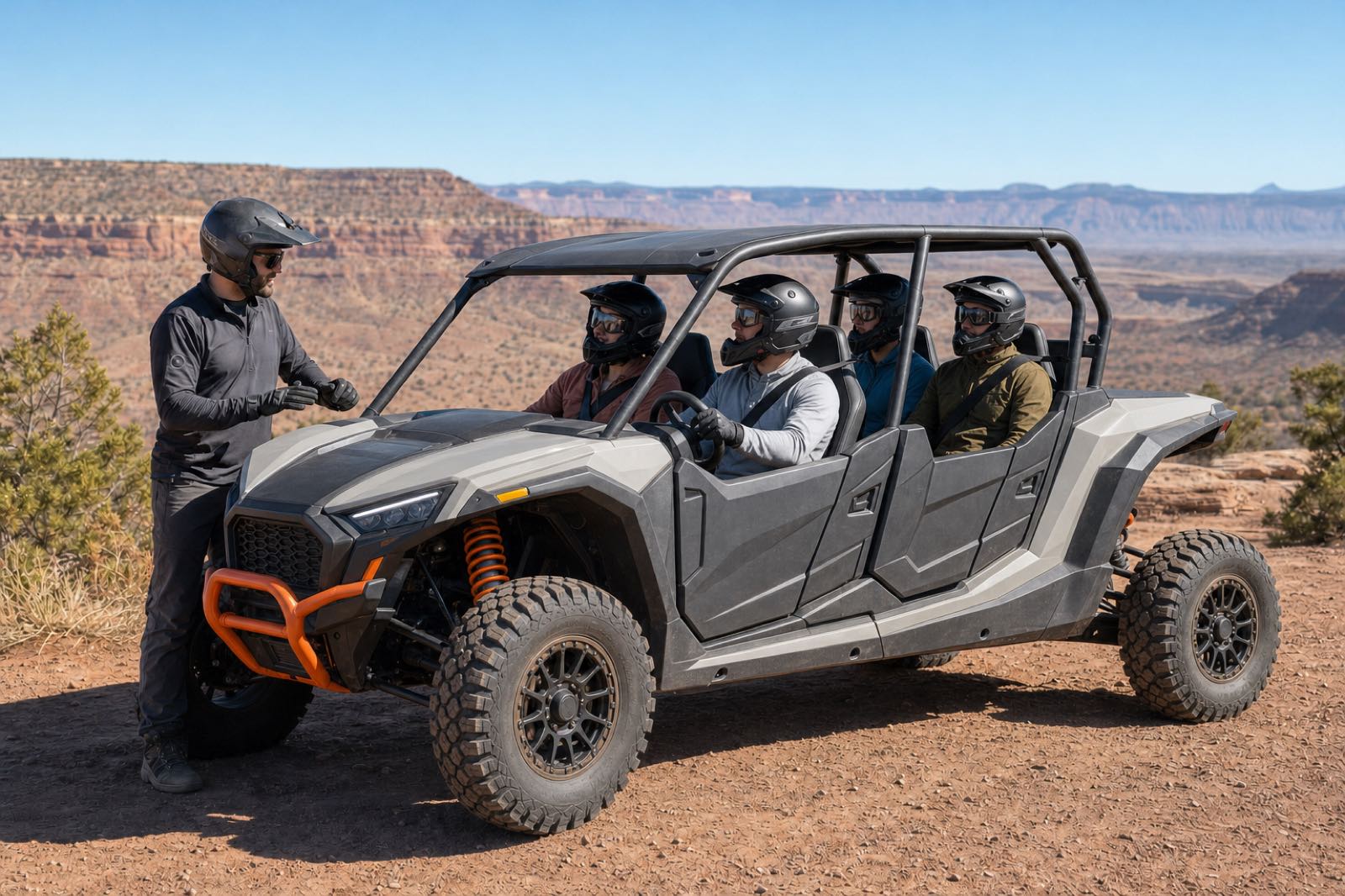 Four helmeted guests seated in a compact four-seat UTV while a mechanic-guide briefs them at a red-rock overlook