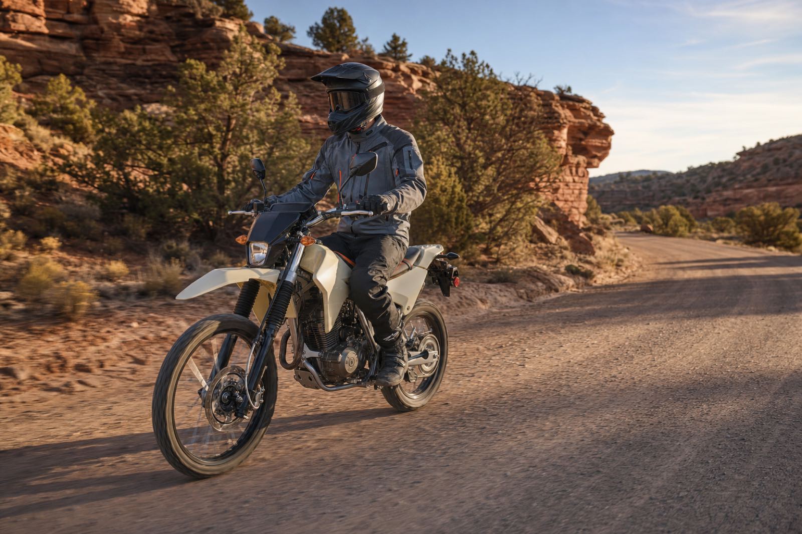 A rider in complete protective equipment traveling at a controlled pace on a graded high-desert trail